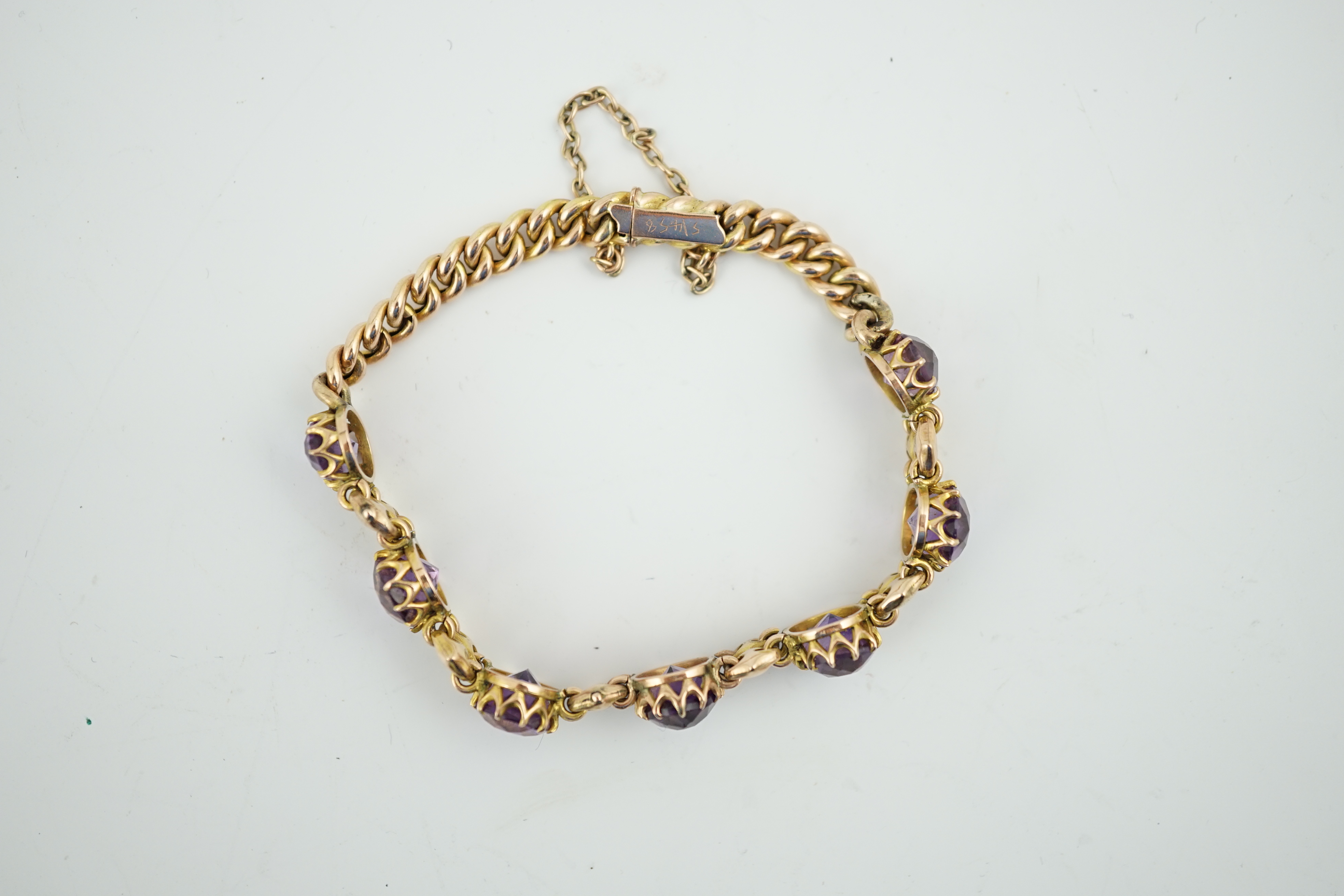 A 9ct gold and graduated seven stone oval cut amethyst set curb link bracelet